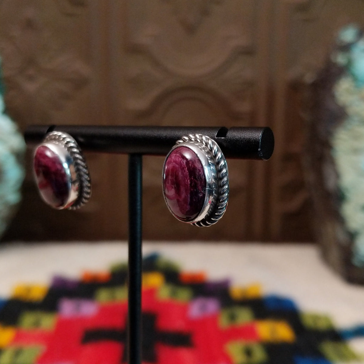 This vibrant Purple Spiny Oyster Shell Oval Earrings set by Priscilla Smith features oval purple shell cabochons set in polished silver with twisted rope-style borders; side view.