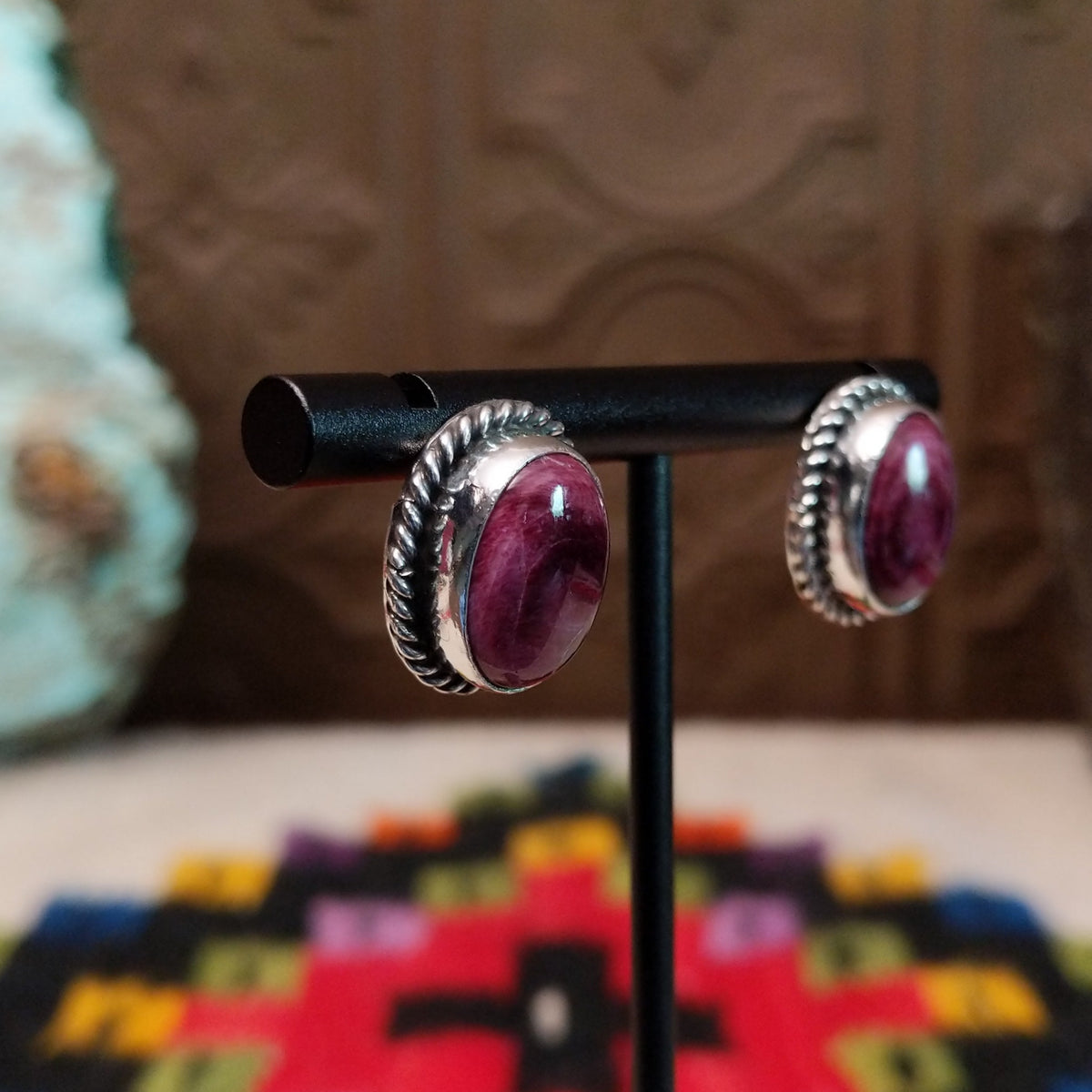 This vibrant Purple Spiny Oyster Shell Oval Earrings set by Priscilla Smith features oval purple shell cabochons set in polished silver with twisted rope-style borders; side view.