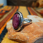 Angled side view of a purple spiny oyster shell ring showing the raised oval setting, textured silver border, and polished split-shank band.