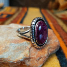 Angled side view of a purple spiny oyster shell ring showing the raised oval setting, textured silver border, and polished split-shank band.