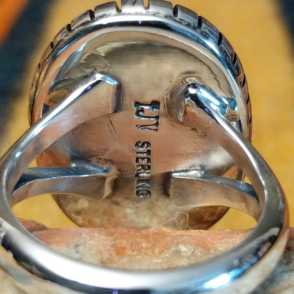 Close up of the artist's stamped signature and the ring's polished split-shank band.