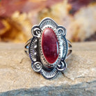 Oval spiny oyster shell set in a notched bezel, framed by ornate, ribbed detailing.