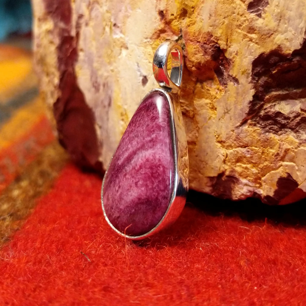 Teardrop shaped sterling silver pendant with purple spiny oyster shell set inside it.