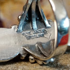 The artisan's signature is stamped on the underside of the bezel.