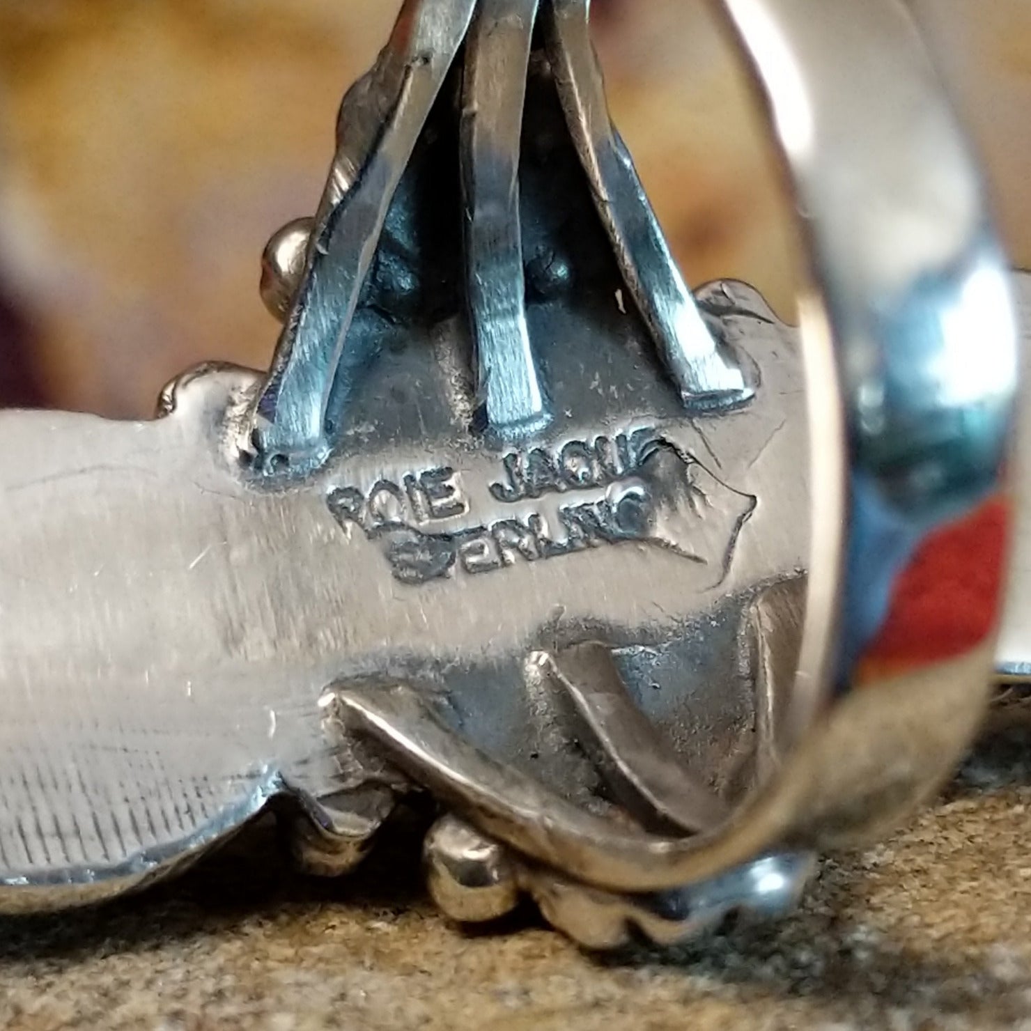 The artisan's signature is stamped on the underside of the bezel.