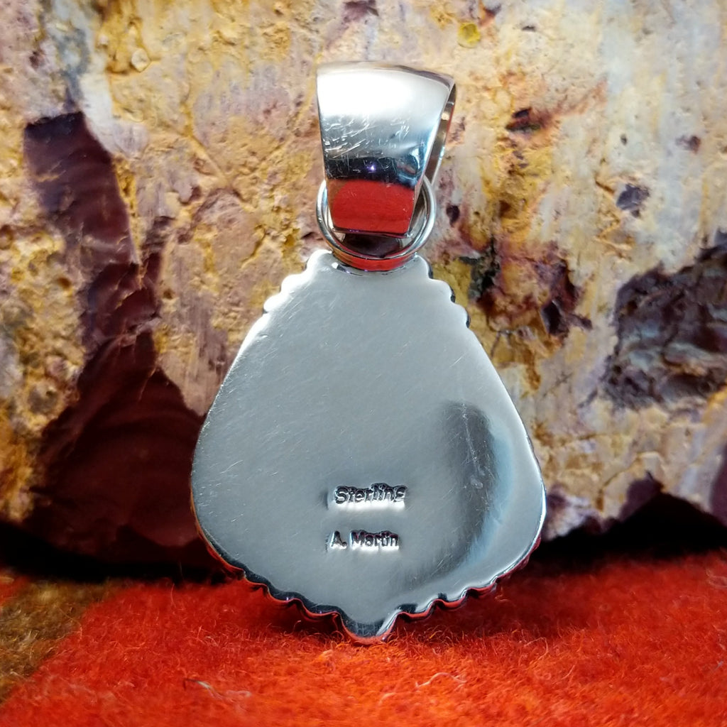 The artisan's signature is stamped on the back of the pendant.