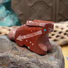 Rabbit Zuni fetish carving by Patrick Wallace in red stone with an engraved arrow motif and turquoise inlaid eye.