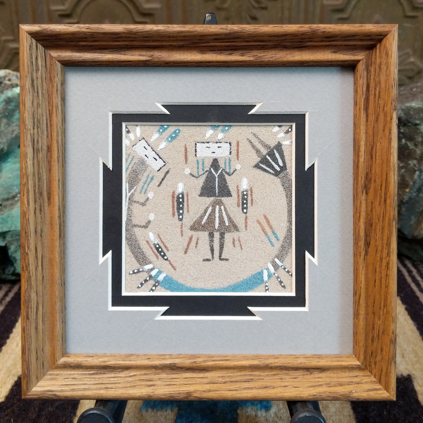 Framed Navajo sand painting of a Rainbow Yei with symbolic motifs.