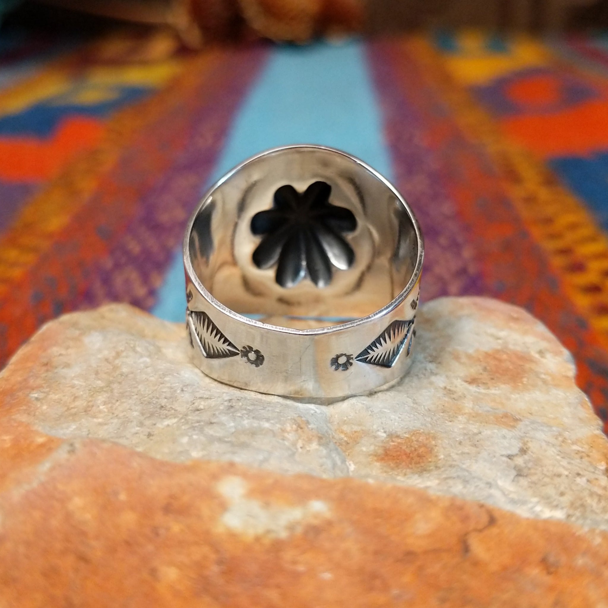 Raised #8 Turquoise Ring by Chris Billie featuring an oval turquoise stone centered within a raised silver flower, surrounded by detailed stamped and oxidized silverwork on a wide band; underside view.