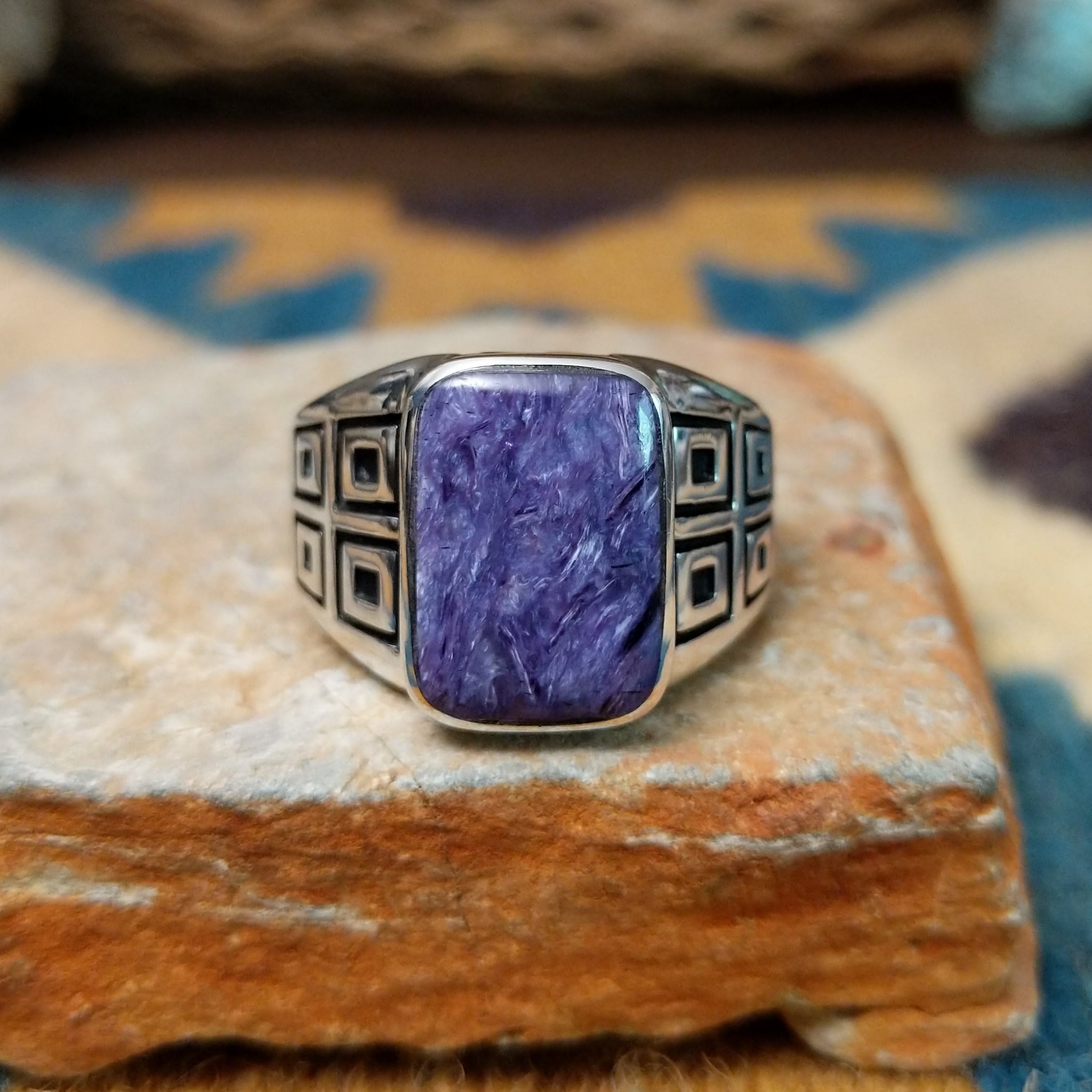 Handcrafted Navajo sterling silver ring by Terry Wood featuring a raised rectangular charoite cabochon with natural purple swirling patterns, set in a polished silver bezel with geometric detailing on the band.