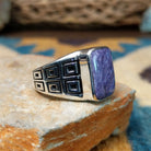 Handcrafted Navajo sterling silver ring by Terry Wood featuring a raised rectangular charoite cabochon with natural purple swirling patterns, set in a polished silver bezel with geometric detailing on the band; side view.