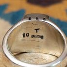 Handcrafted Navajo sterling silver ring by Terry Wood featuring a raised rectangular charoite cabochon with natural purple swirling patterns, set in a polished silver bezel with geometric detailing on the band; artisan and Sterling Silver stamp.
