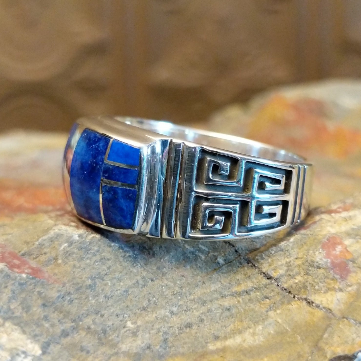 Sterling silver ring with lapis inlaid on the raised bezel and geometric designs on the band.