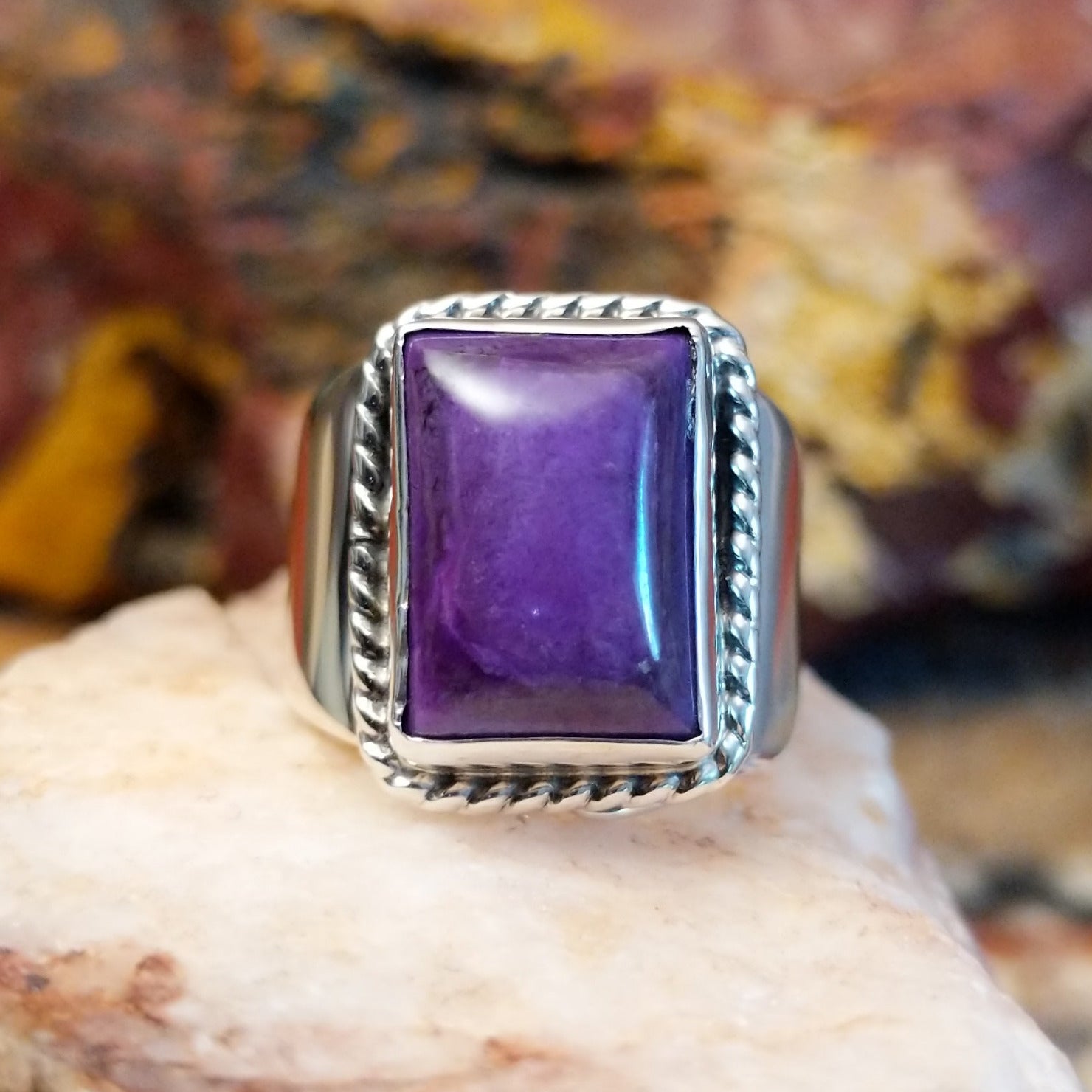 Sterling silver ring with sugilite set in a raised bezel with twisted rope accents, and a polished finish.