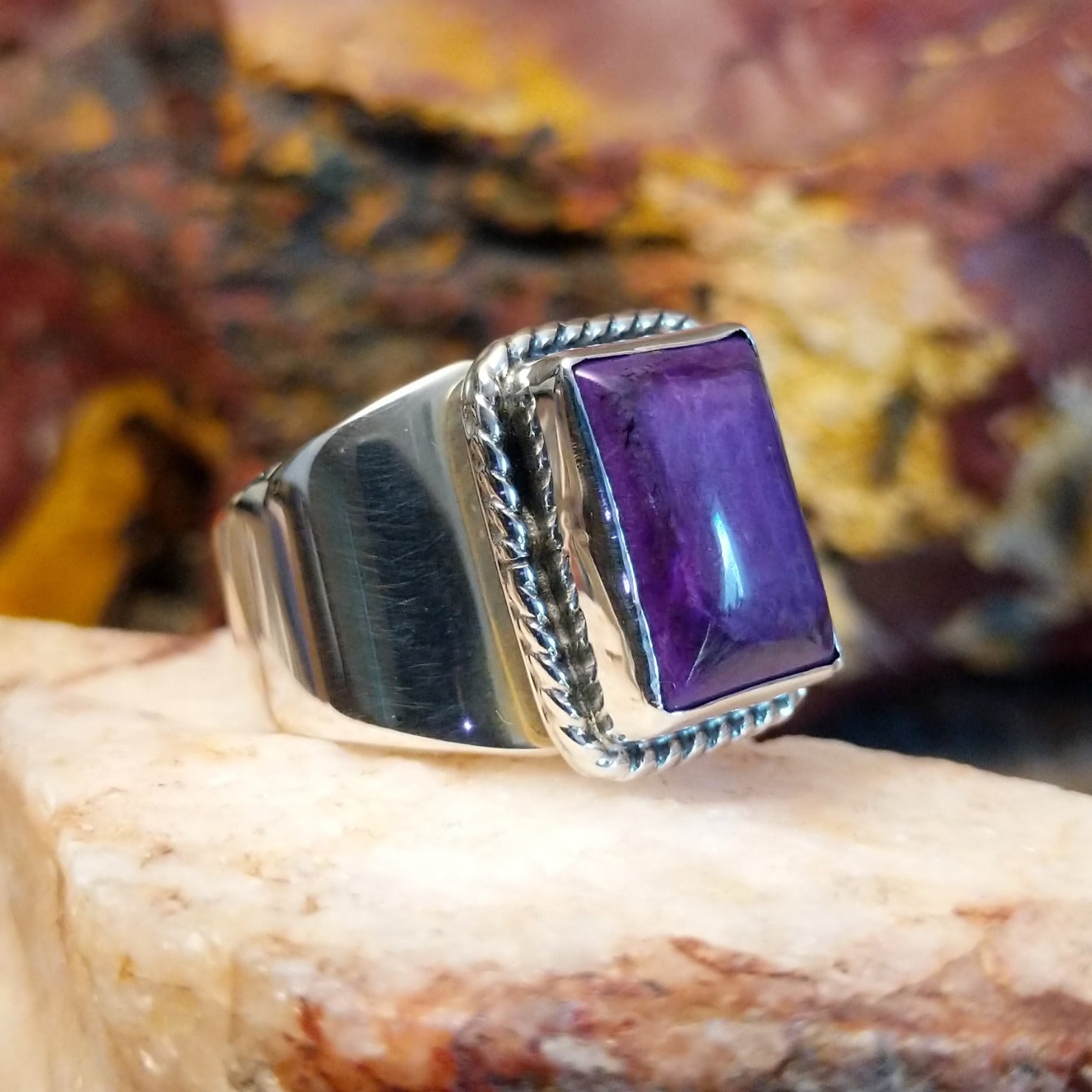 Sterling silver ring with sugilite set in a raised bezel with twisted rope accents, and a polished finish.