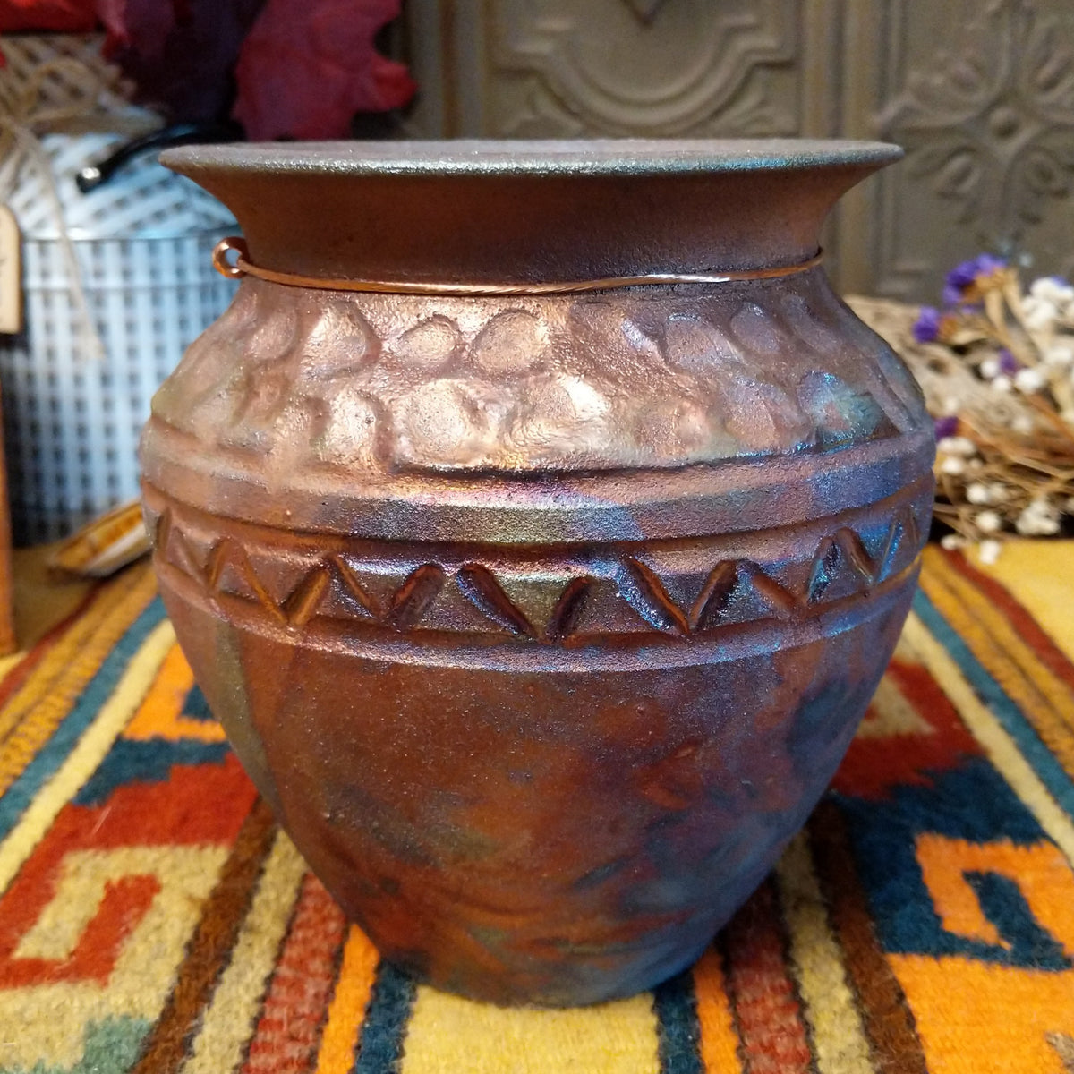 Round raku pottery vase by Roger Calhoun with a flared rim, raised geometric bands, and a metallic copper, bronze, and smoky brown finish.