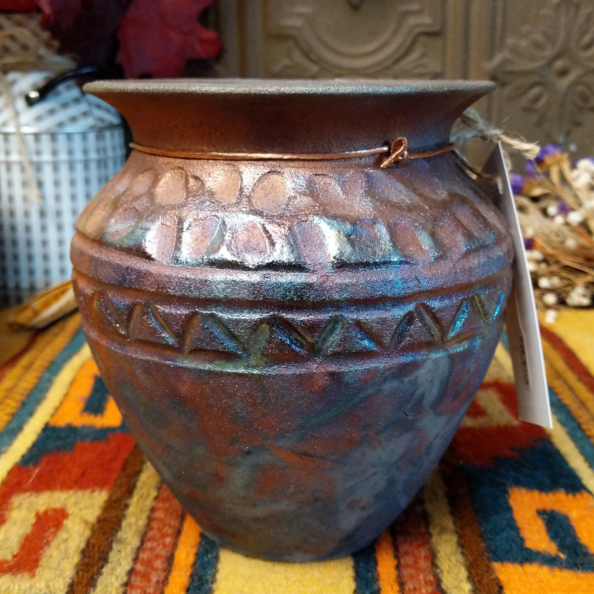 Round raku pottery vase by Roger Calhoun with a flared rim, raised geometric bands, and a metallic copper, bronze, and smoky brown finish.