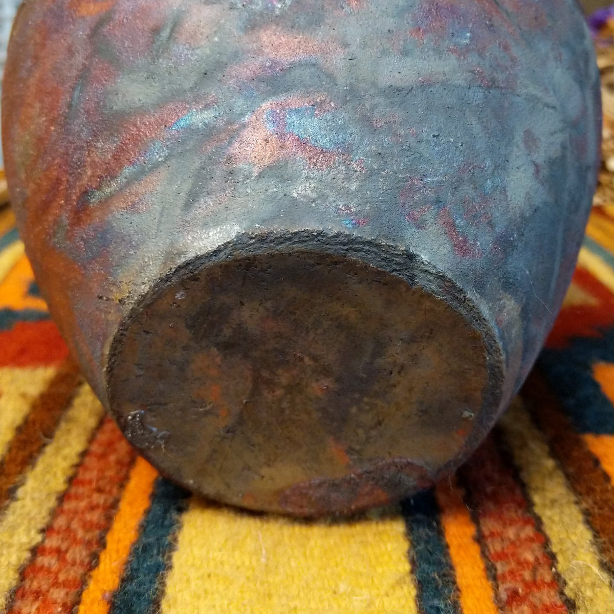 Round raku pottery vase by Roger Calhoun with a flared rim, raised geometric bands, and a metallic copper, bronze, and smoky brown finish.