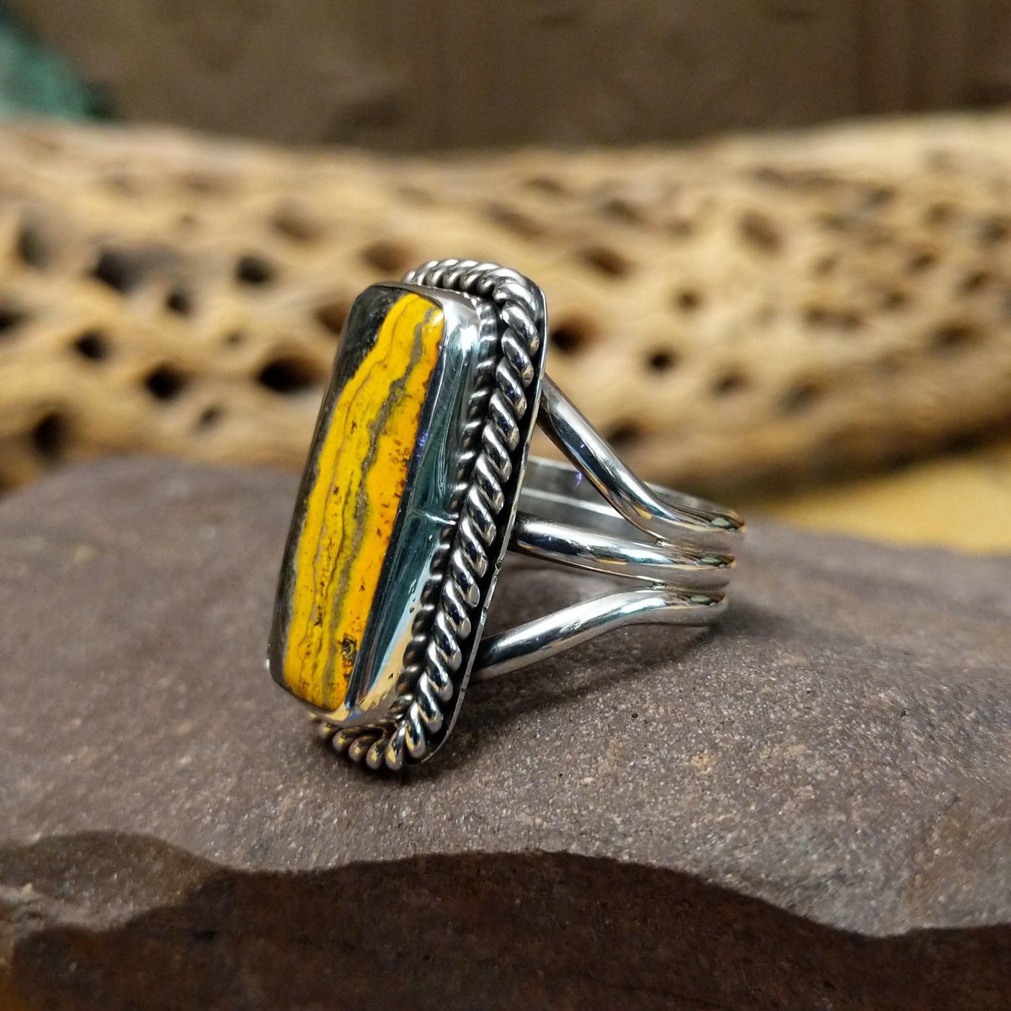 Rectangle bumblebee jasper ring by Terry Wood, featuring a vibrant rectangular bumblebee jasper stone with natural yellow, orange, black, and gray patterns set in a handcrafted sterling silver band.  Side view.