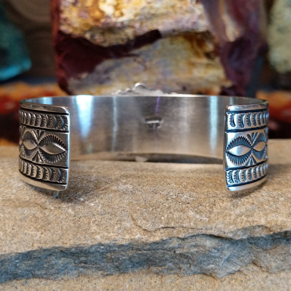 The ornate polished silver band of the cuff.