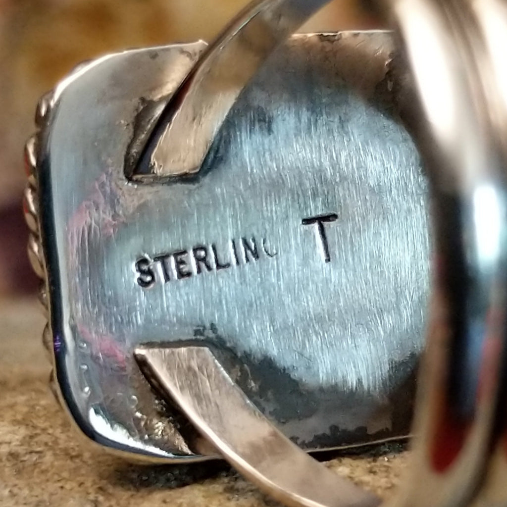 The artist's initials are stamped on the inside of the setting.