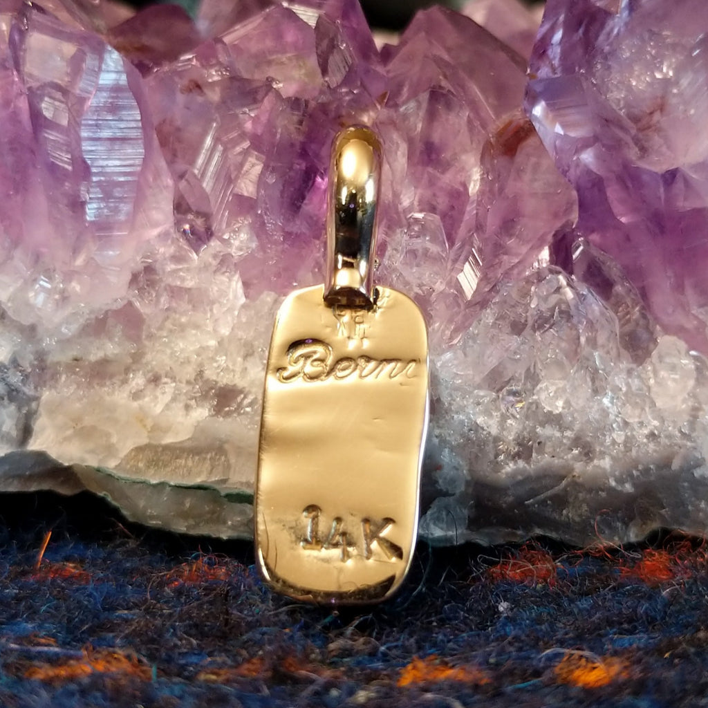 The back of the pendant features the artist's signature and gold stamp.