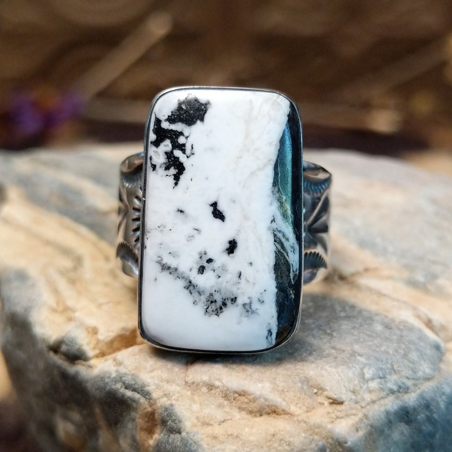 Sterling silver ring with white buffalo stone set in a rectangular bezel and stamped designs on the band.