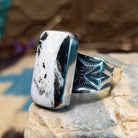 Sterling silver ring with white buffalo stone set in a rectangular bezel and stamped designs on the band.