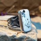 Sterling silver ring with white buffalo stone set in a rectangular bezel and stamped designs on the band.