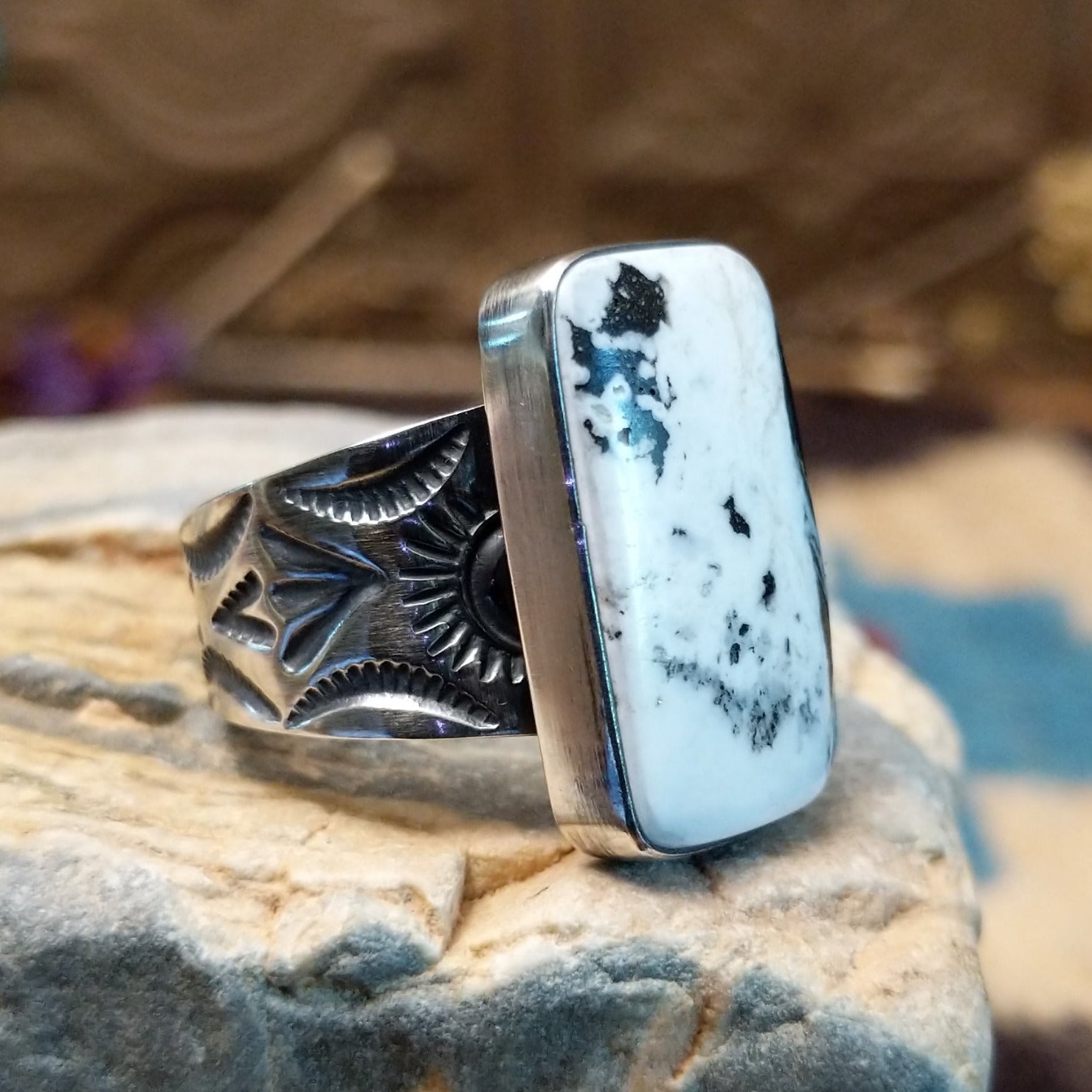 Sterling silver ring with white buffalo stone set in a rectangular bezel and stamped designs on the band.