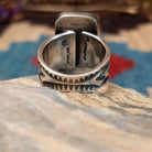 Sterling silver ring with white buffalo stone set in a rectangular bezel and stamped designs on the band.