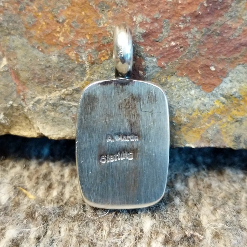 The back of the pendant features the brushed sterling silver and artist's signature.