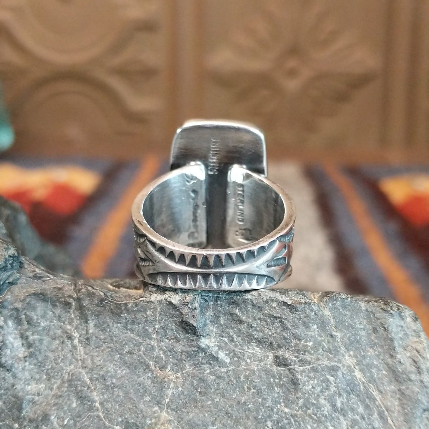 The ring's band is stamped with intricate details.