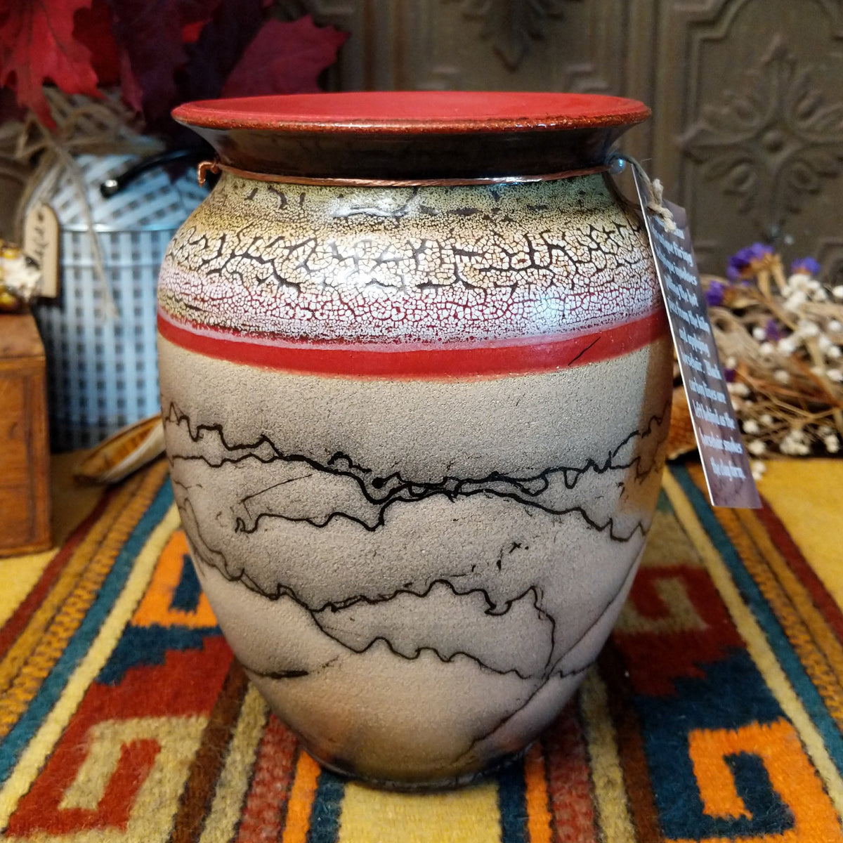 Rounded horsehair pottery vase by Roger Calhoun with a wide red rim, multicolored crackled shoulder, red accent band, and black horsehair markings across a cream-colored body.
