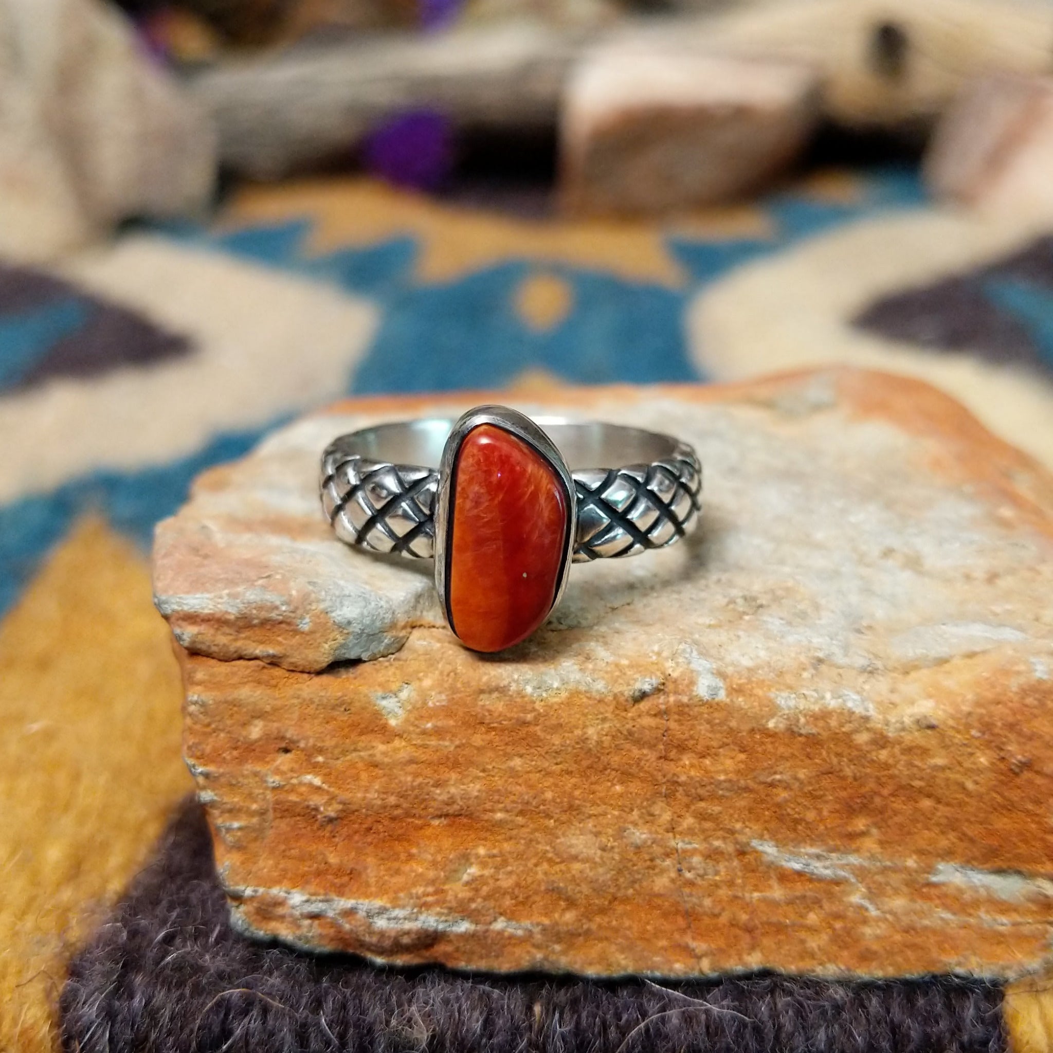 Sterling silver Red Spiny Oyster Shell ring by Raymond Coriz with a hand-stamped band and oval red gemstone.