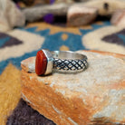 Sterling silver Red Spiny Oyster Shell ring by Raymond Coriz with a hand-stamped band and oval red gemstone; side view.