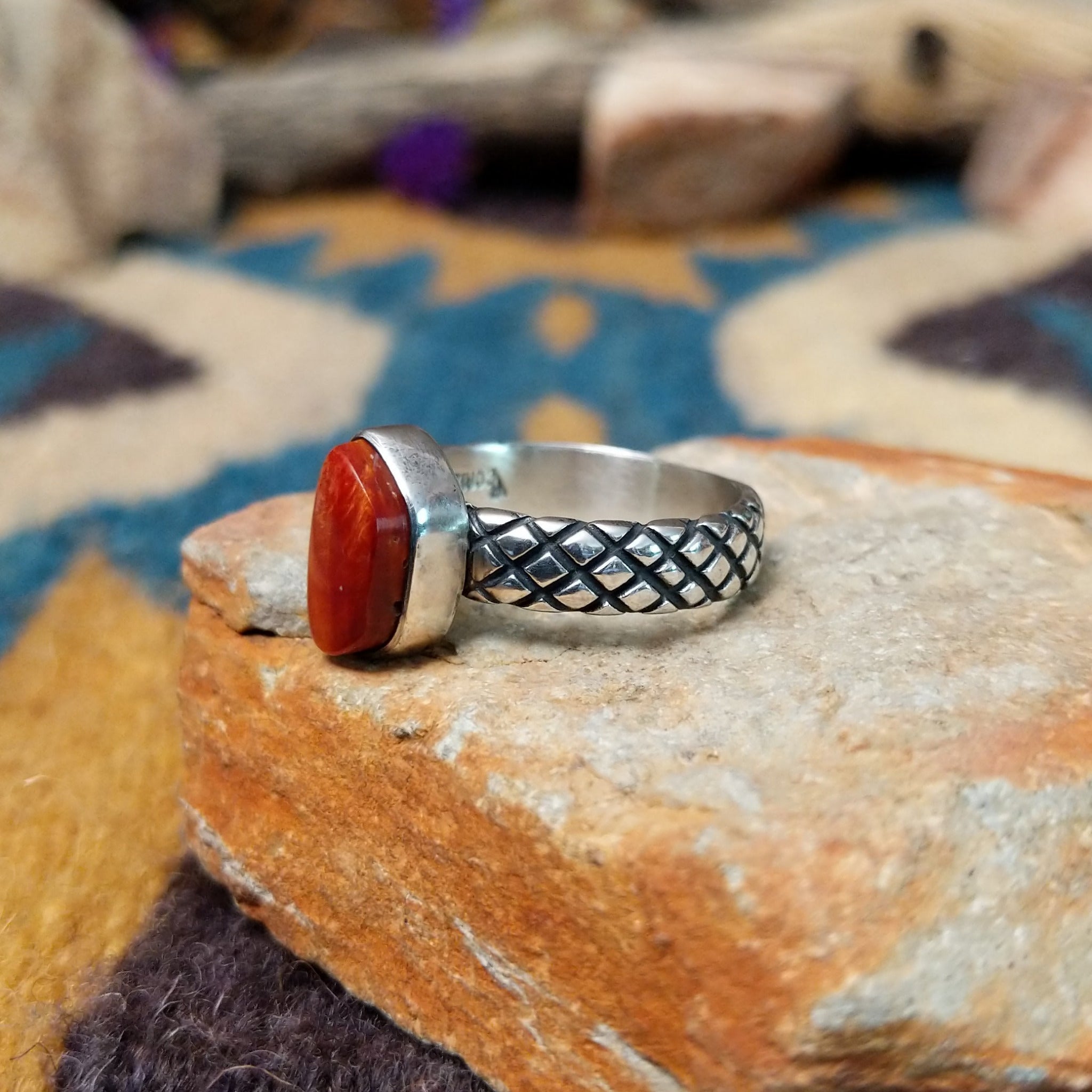 Sterling silver Red Spiny Oyster Shell ring by Raymond Coriz with a hand-stamped band and oval red gemstone; side view.