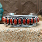 Sterling silver cuff bracelet with red spiny oyster shell set in oval bezels, lined along the surface and twisted rope with dotted accents.