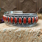 Sterling silver cuff bracelet with red spiny oyster shell set in oval bezels, lined along the surface and twisted rope with dotted accents.