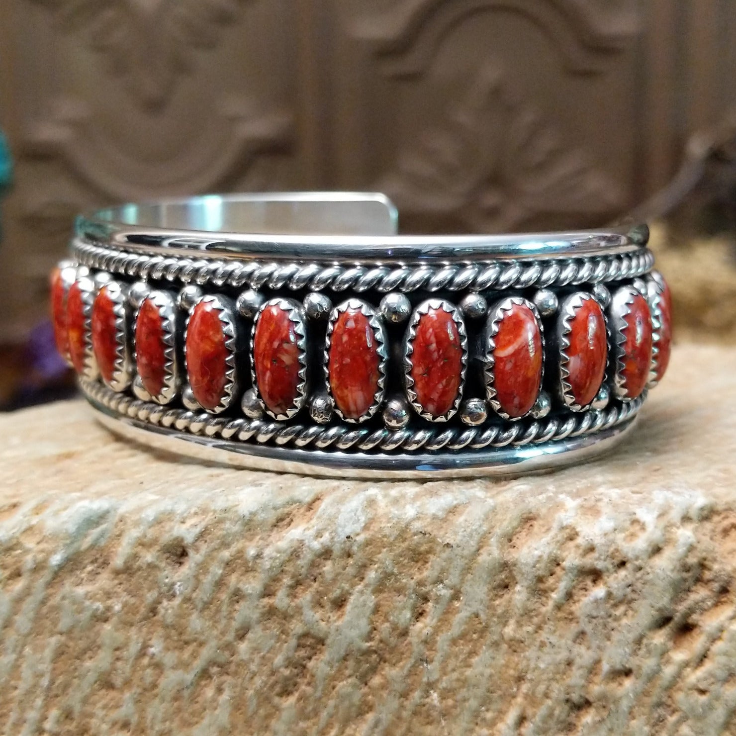 Sterling silver cuff bracelet with red spiny oyster shell set in oval bezels, lined along the surface and twisted rope with dotted accents.