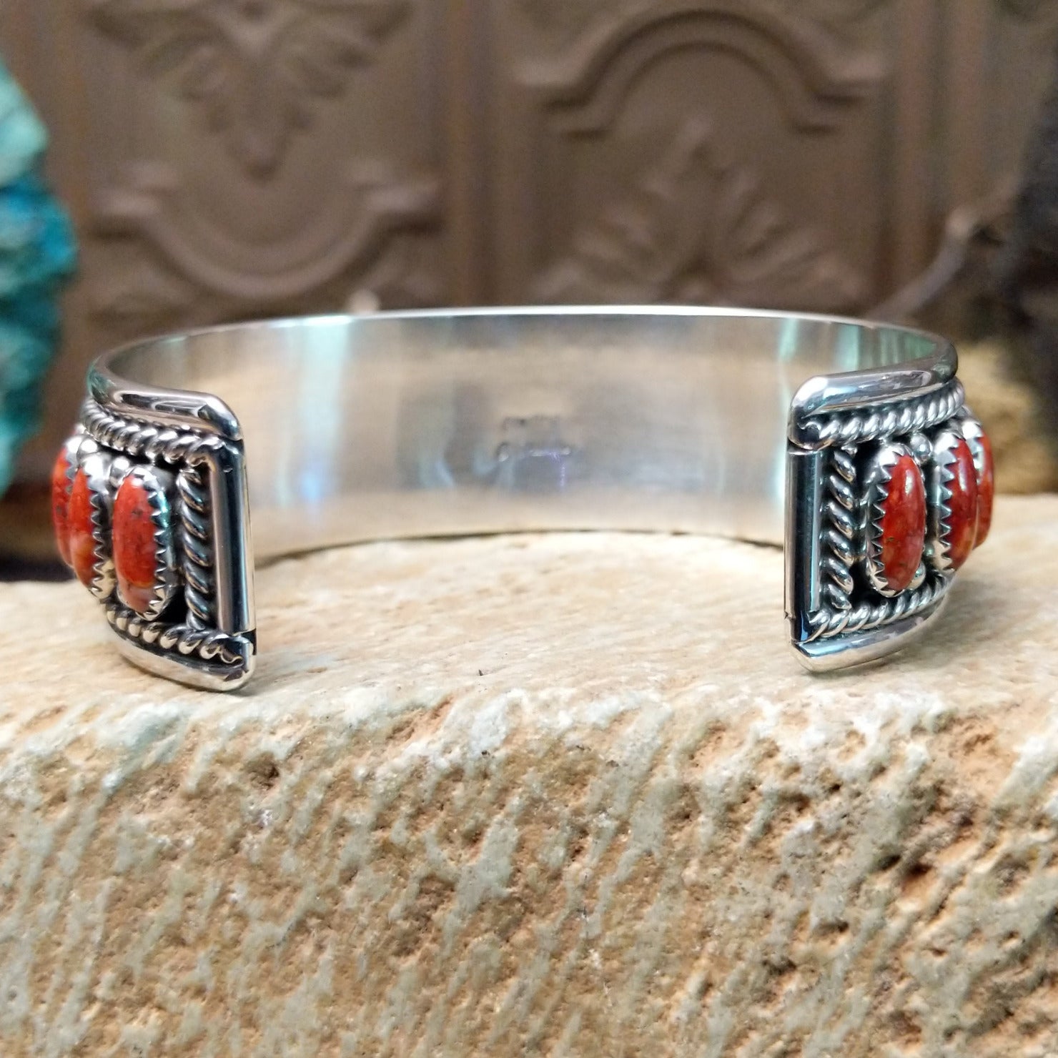 Sterling silver cuff bracelet with red spiny oyster shell set in oval bezels, lined along the surface and twisted rope with dotted accents.