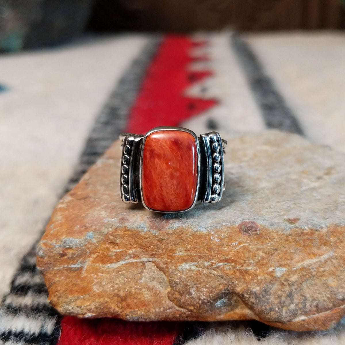Red spiny oyster shell ring by Akee Douglas with five-row twisted silver band.