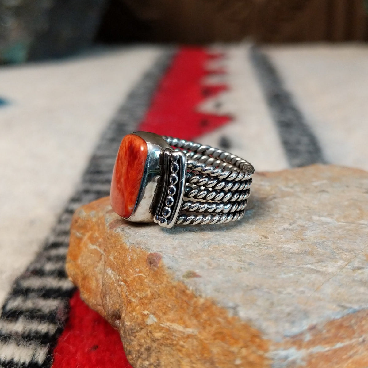 Red spiny oyster shell ring by Akee Douglas with five-row twisted silver band.