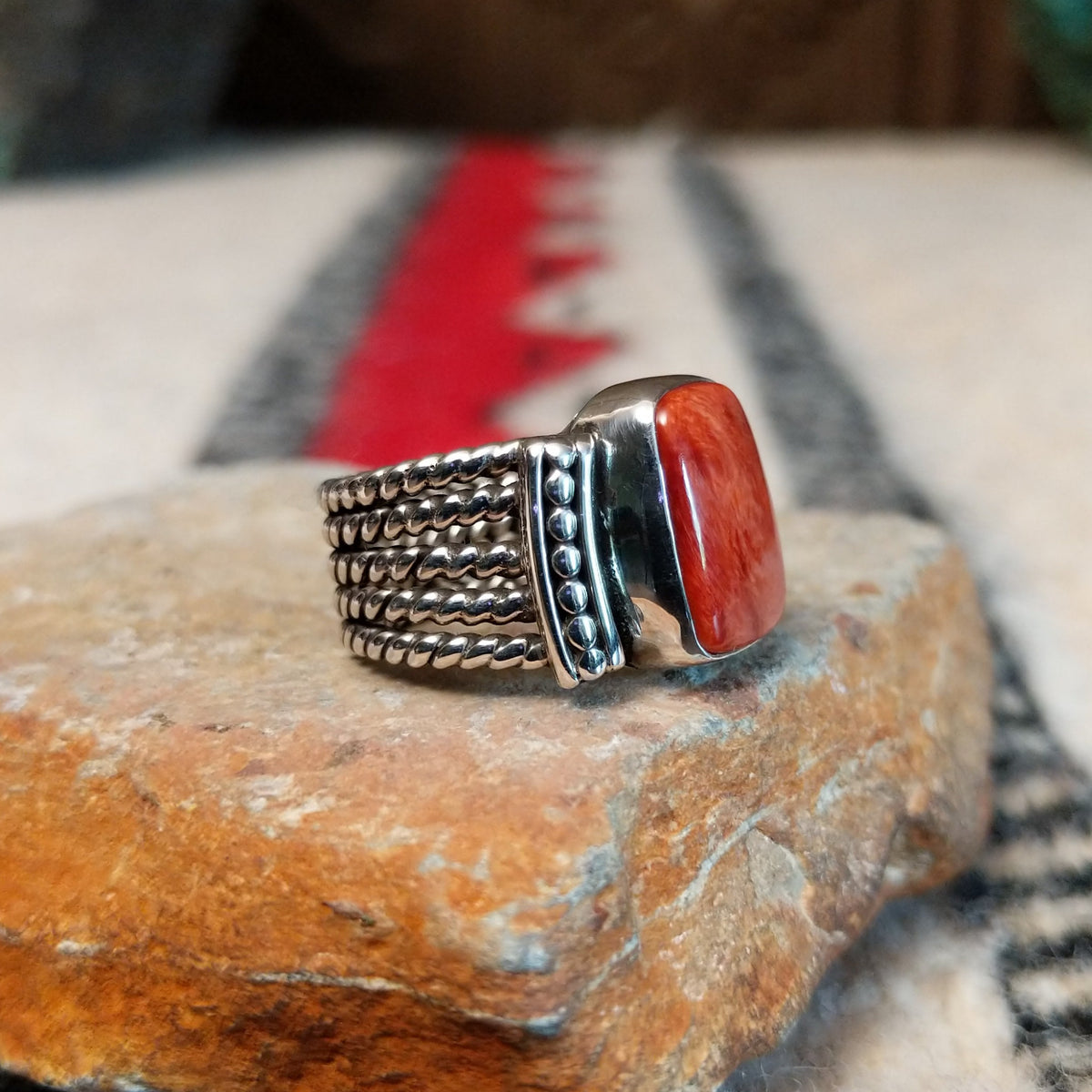 Red spiny oyster shell ring by Akee Douglas with five-row twisted silver band.