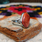 Red spiny oyster shell ring by Bernyse Chavez with an irregular polished stone and split silver band.