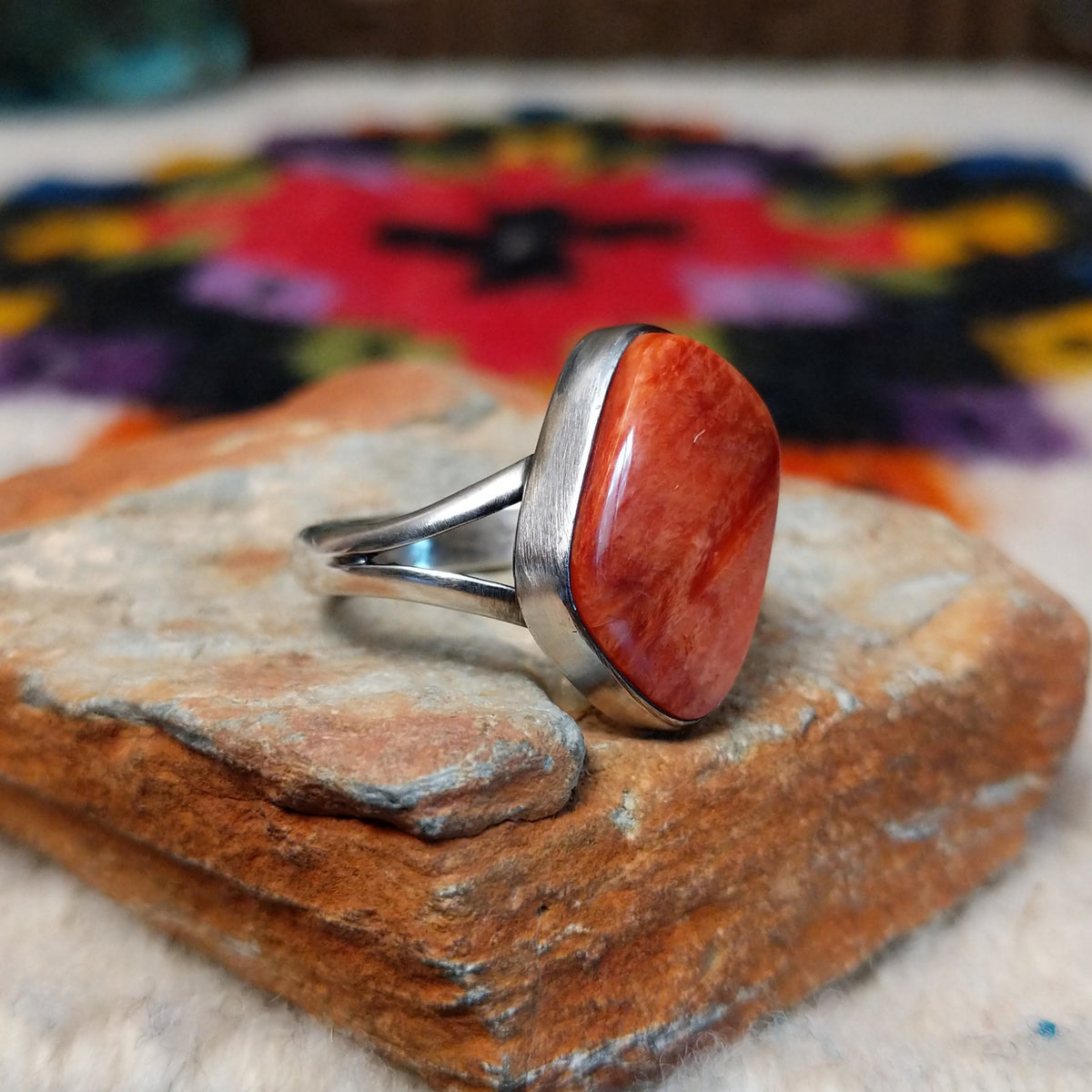 Red spiny oyster shell ring by Bernyse Chavez with an irregular polished stone and split silver band.