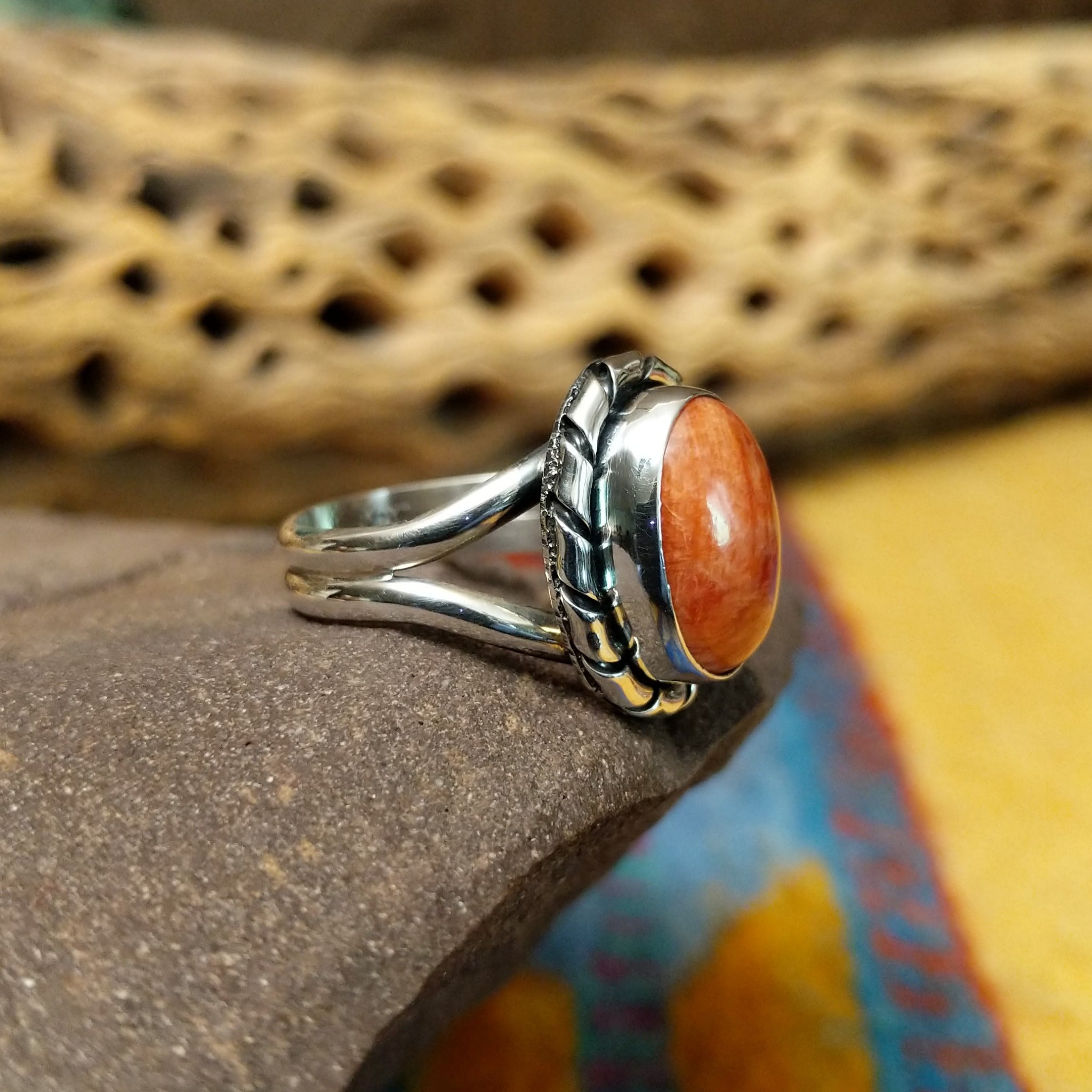 Red spiny oyster shell ring by Terry Wood, featuring a vibrant red spiny oyster shell set in a handcrafted sterling silver band with traditional Southwestern-inspired metalwork.  Side view.