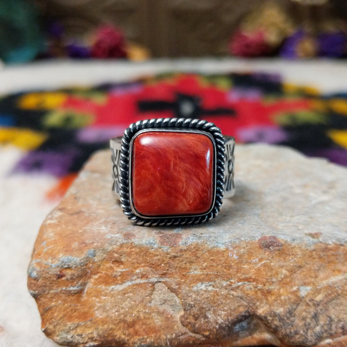 Red Spiny Oyster Shell Ring by Raymond Coriz with a square red-orange cabochon, twisted rope-style sterling silver border, and stamped silver band.