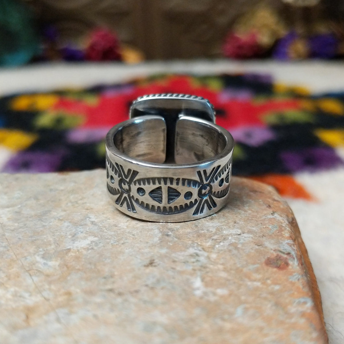 Red Spiny Oyster Shell Ring by Raymond Coriz with a square red-orange cabochon, twisted rope-style sterling silver border, and stamped silver band; underside view.