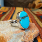 Redskin Turquoise Ring by Everett & Mary Teller featuring a large oval sky-blue turquoise stone with distinctive brown spiderweb matrix, a smooth polished surface, and a simple silver bezel setting; side view.